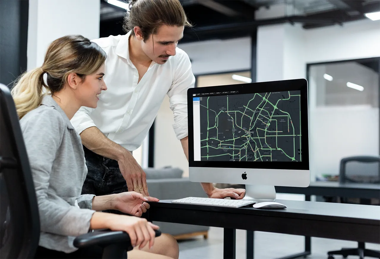 Two colleagues at a desktop computer reviewing a city map on screen